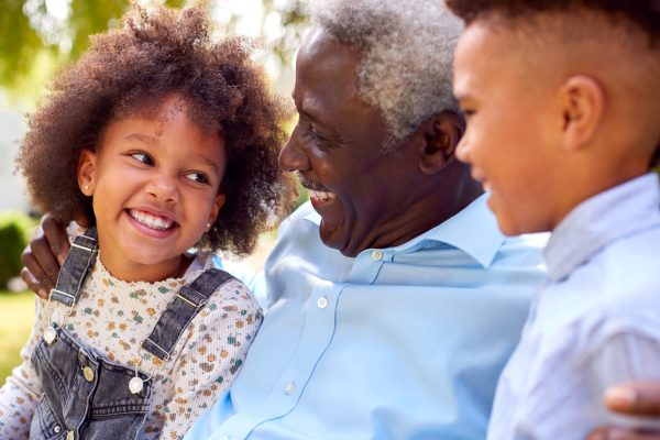 Loving,grandfather,talking,with,grandchildren,in,garden,at,home